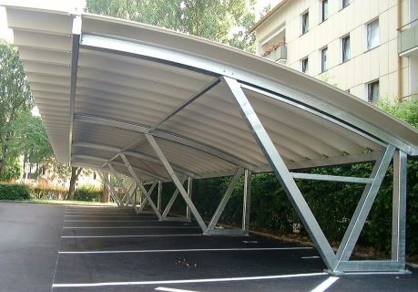 Großflächiger Carport aus Metall von P&K Metallbau, bietet umfassenden Schutz für Fahrzeuge auf einem Parkplatz.