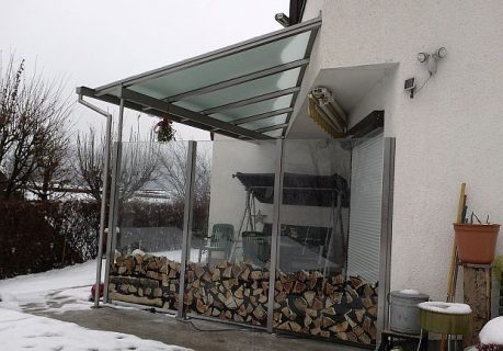 Überdachter Außenbereich mit integriertem Holzlager, installiert von P&K Metallbau, zeigt Langlebigkeit auch im Winter.